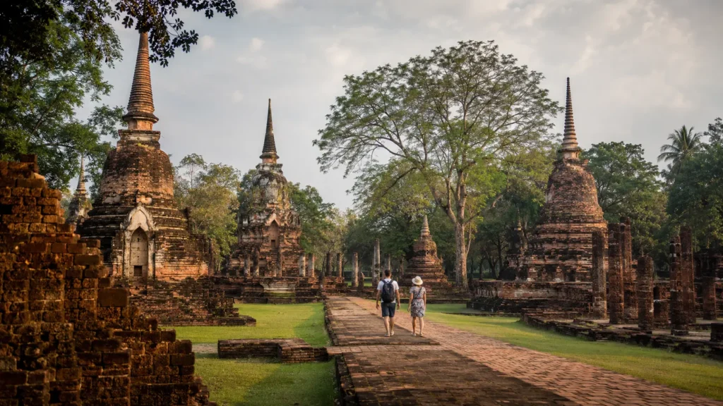 Travellers walking among ancient temples at Si Satchanalai Historical Park